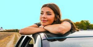 smiling woman looking out of car window thinking of her long distance relationship