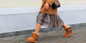 woman in skirt and boots walking on sidewalk