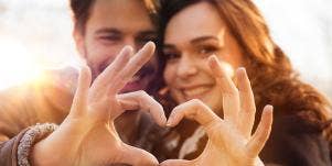 man and woman making heart with their hands