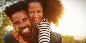 Black couple, man with beard, woman with natural hair, hug while backlit