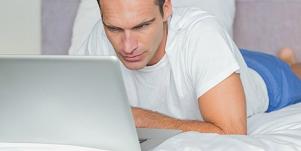 man looking at laptop in bed