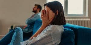 woman putting hand over eyes next to man on couch