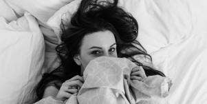 woman covering face under sheets