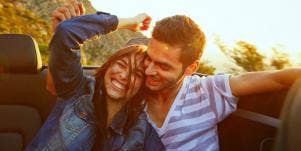 couple laughing in a convertible driving