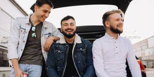 group of guy friends hanging out sitting on back of car