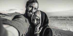 man taking photo with woman on beach