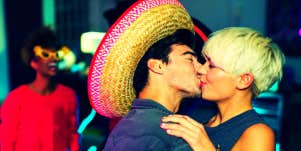 woman kissing man in a sombrero