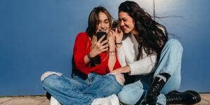 young girls looking at the phone laughing