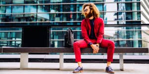man in red suit sitting on a bench outside