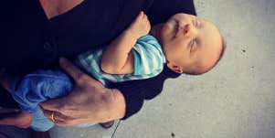 A woman's arm holding a newborn baby, both caucasian 