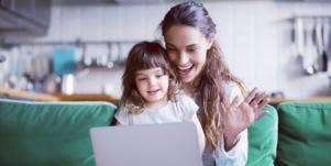 woman with little girl on her lap waving at a computer