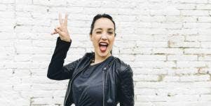 woman smiling with peace sign against wall