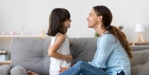 mother and little girl sitting on couch smiling