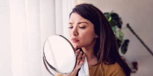woman looking at her face in the mirror