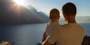 father holding baby looking at water