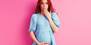 pregnant woman looking surprised in front of pink background