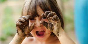 child with mud on hands