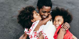 mother and two daughters cuddling on a beach