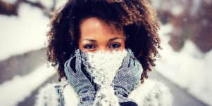 black woman with natural hair in the snow, scarf over mouth, big brown eyes look at camera