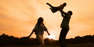 silhouette of two parents playing with child 