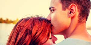 Handsome young man kissing the top of his girlfriend's head