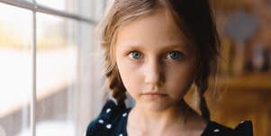 grade-school age girl in braids looks solemnly at camera
