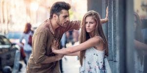 scared woman pushing angry man away