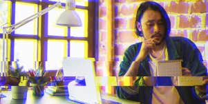 asian man sitting at a desk looking at a calendar