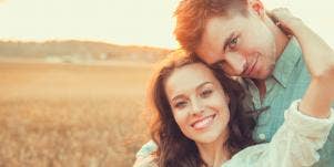smiling man and woman cuddling at a field