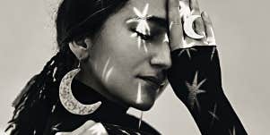 black and white image of a woman in moon earrings with stars projected on her face