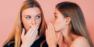 women whispering and covering their mouths