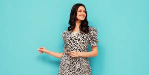 Woman in dress standing against blue background