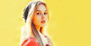 Young blonde woman against yellow wall