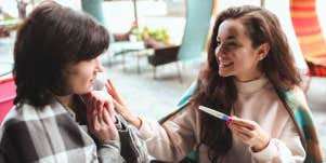 woman announcing pregnancy to friend at restaurant