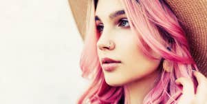 woman with pink hair and hat, looking slightly away