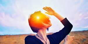 woman in desert, shielding herself from the sun with her hand