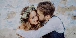 man nuzzling woman with flower crown