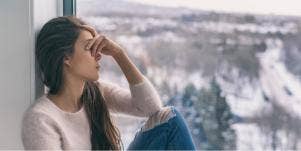 sad woman sitting by window in winter