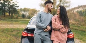 couple in sweats leaning against a car
