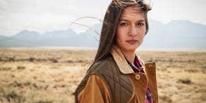 woman standing in desert in brown coat