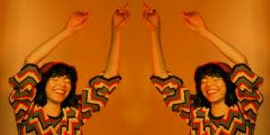 woman with her arms up in the air on orange background