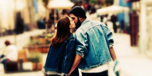 couple walking down the road sharing a kiss