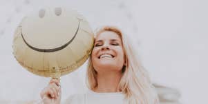 Woman with smiley face balloon looking happy and content
