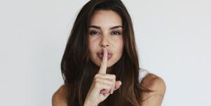 woman with finger on mouth shushing secret