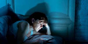man in bed looking at phone nighttime