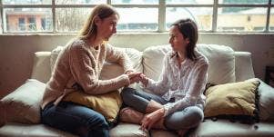 mother talking to young daughter on couch