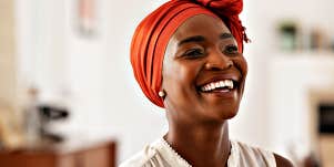 Lovely Black woman in orange hair wrap, smiling joyfully