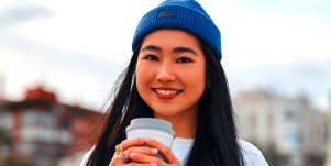 woman in blue beanie holding coffee