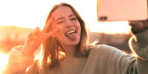 woman taking a selfie holding up a peace sign