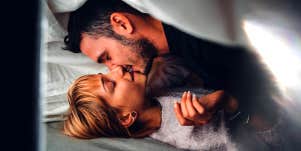 man kissing woman in bed